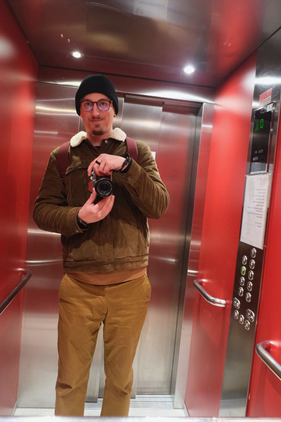 Matej Holek taking a mirror photo with his camera in a red lift