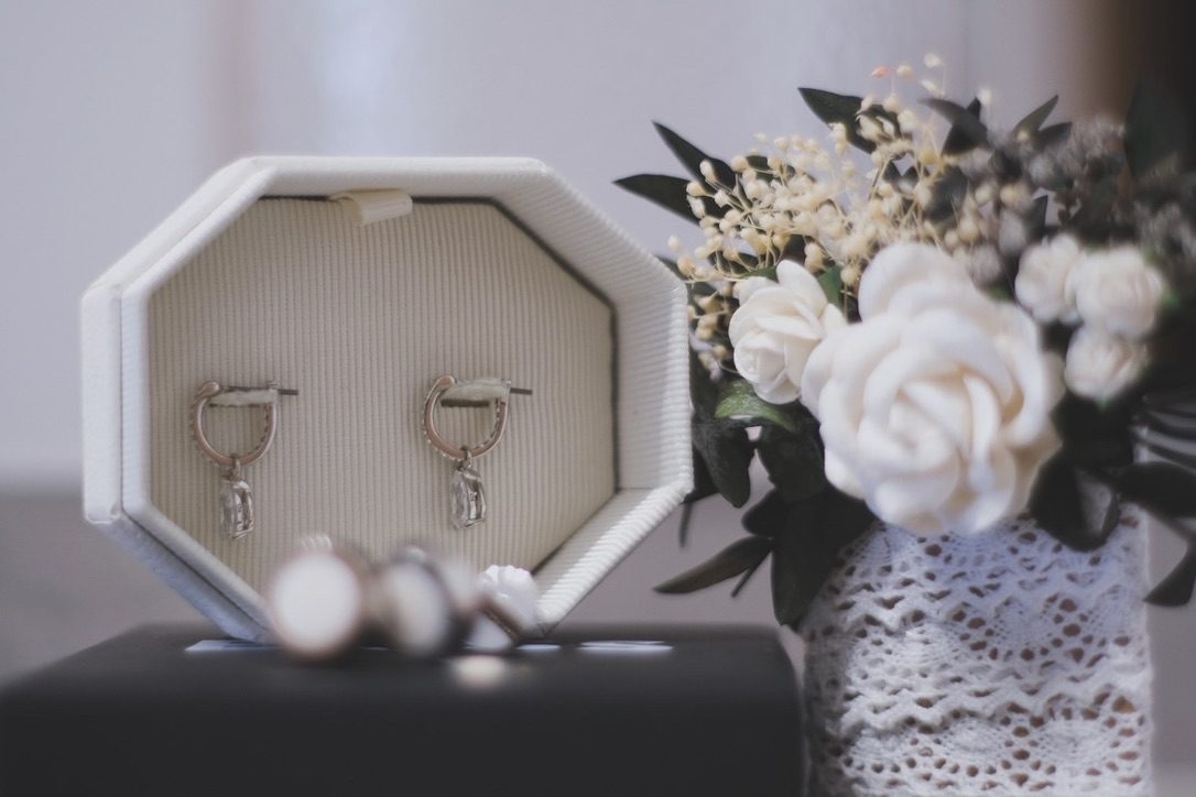 Earrings in a white box next to flowers